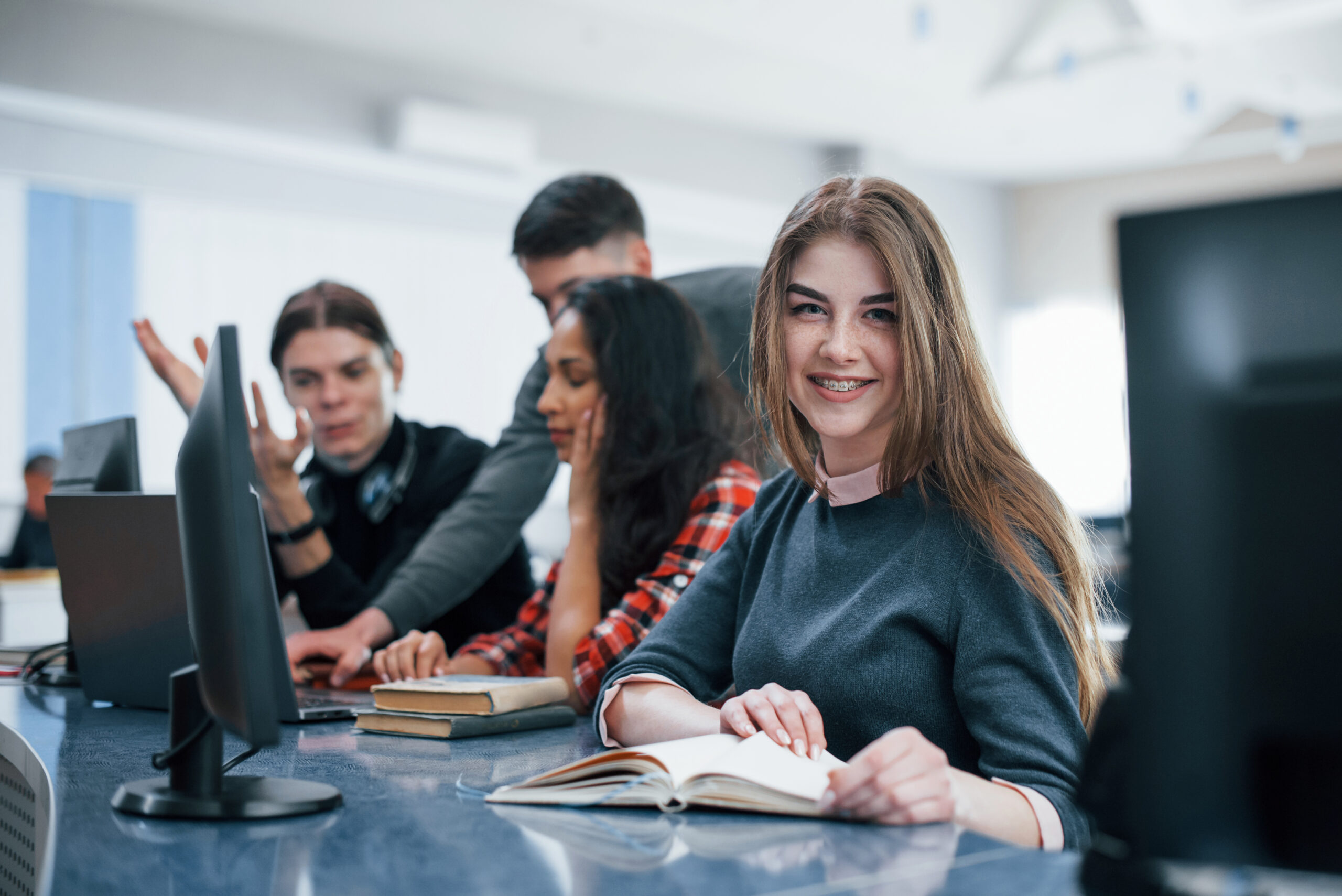 Blonde girl smiling. Group of young people in casual clothes working in the modern office Blonde girl smiling. Group of young people in casual clothes working in the modern office.