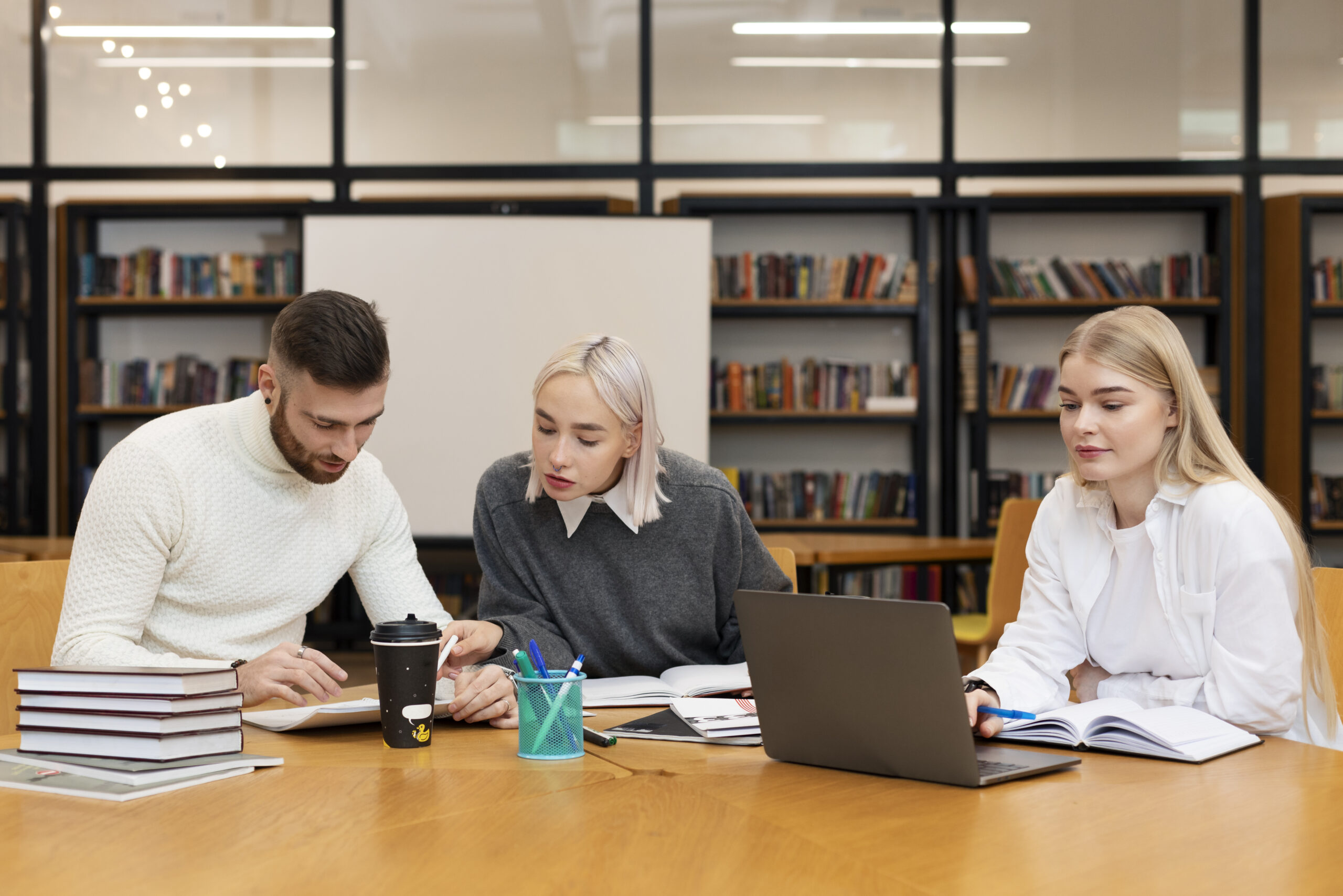 trois-amis-etudiant-a-partir-de-documents-et-d-un-ordinateur-portable-dans-une-bibliotheque trois-amis-etudiant-a-partir-de-documents-et-d-un-ordinateur-portable-dans-une-bibliotheque